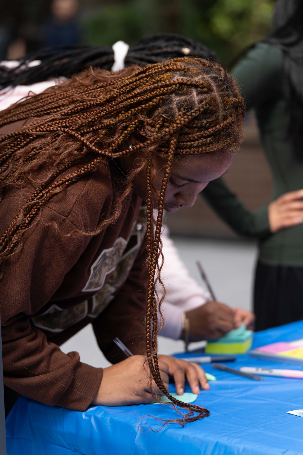 A student leaning over the table writing a note for the Gratitude Wall