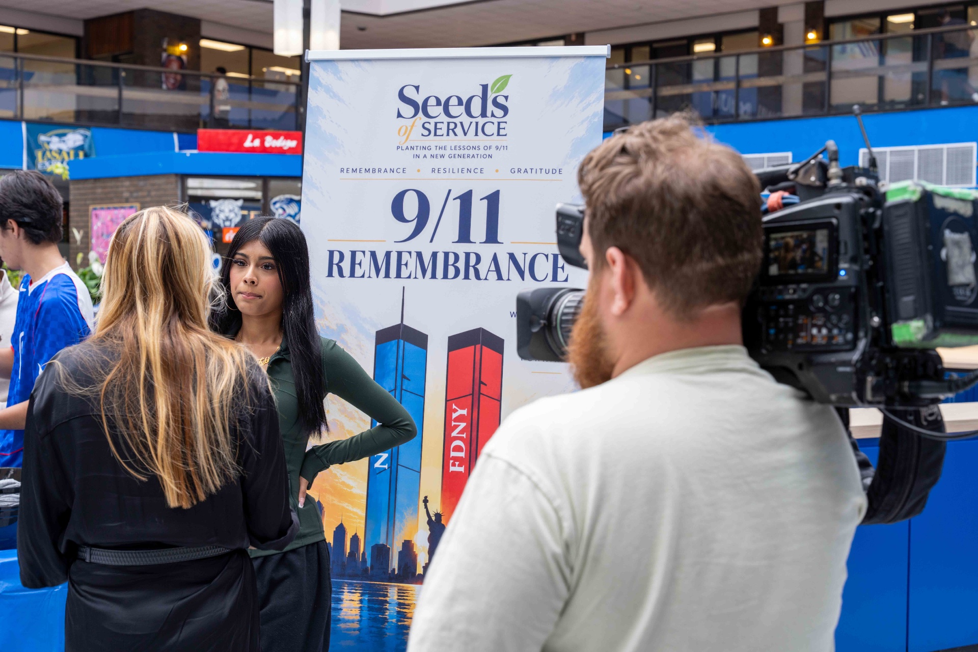 A student being interviewed in front of the Seeds of Service 9/11 Remembrance banner